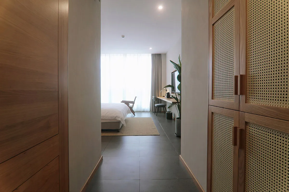 A minimalist bedroom with wooden furniture and a white bed.