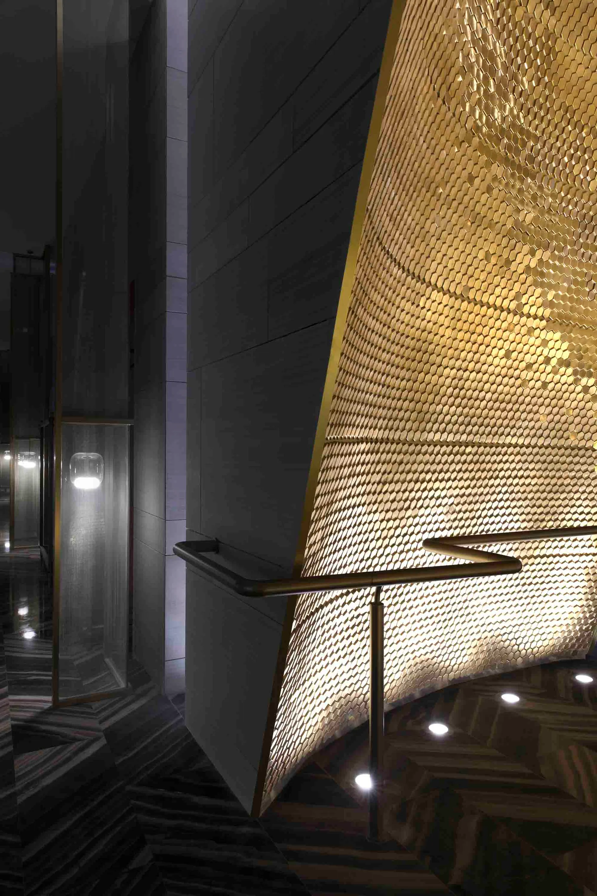 Staircase with a metal hexagon pattern illuminated by lights overhead