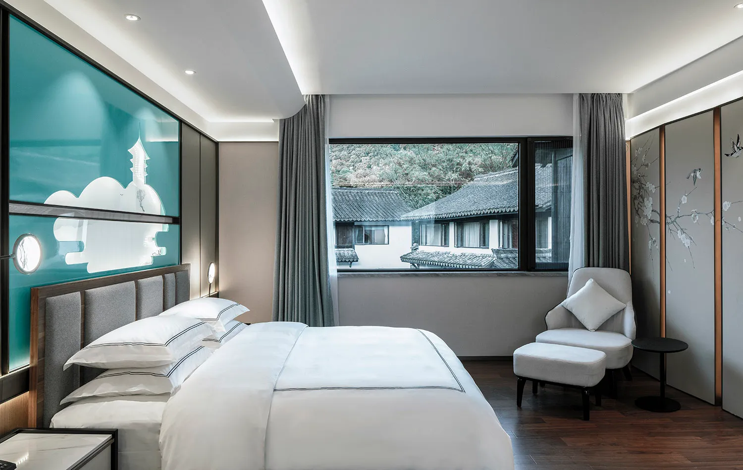 A minimalist bedroom featuring a white fabric bed and modern furniture.