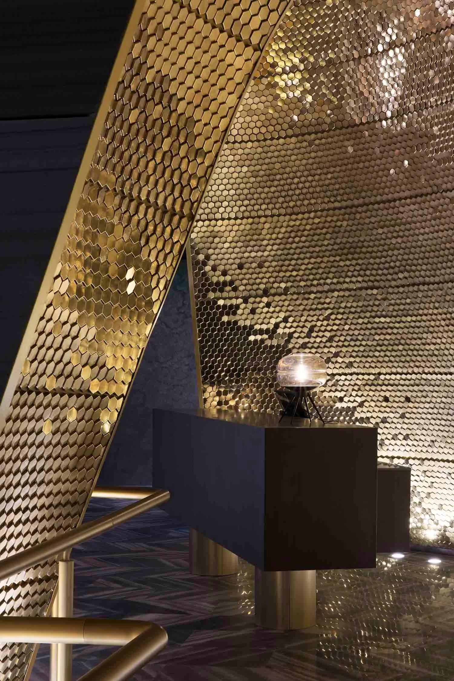 Modern hotel reception area with metallic hexagonal patterns on walls and floors.