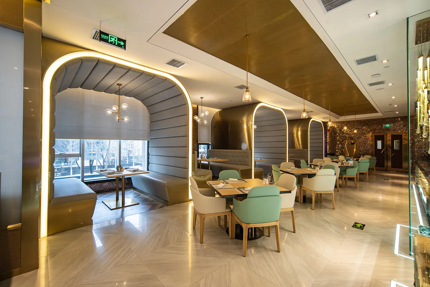 Modern, industrial-themed restaurant interior featuring metallic finishes, polished marble accents, and textured fabric seati