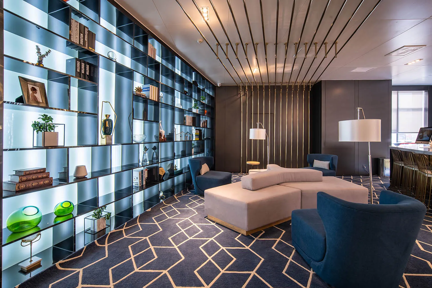 A modern lobby with glass walls, metal accents, and fabric seating.
