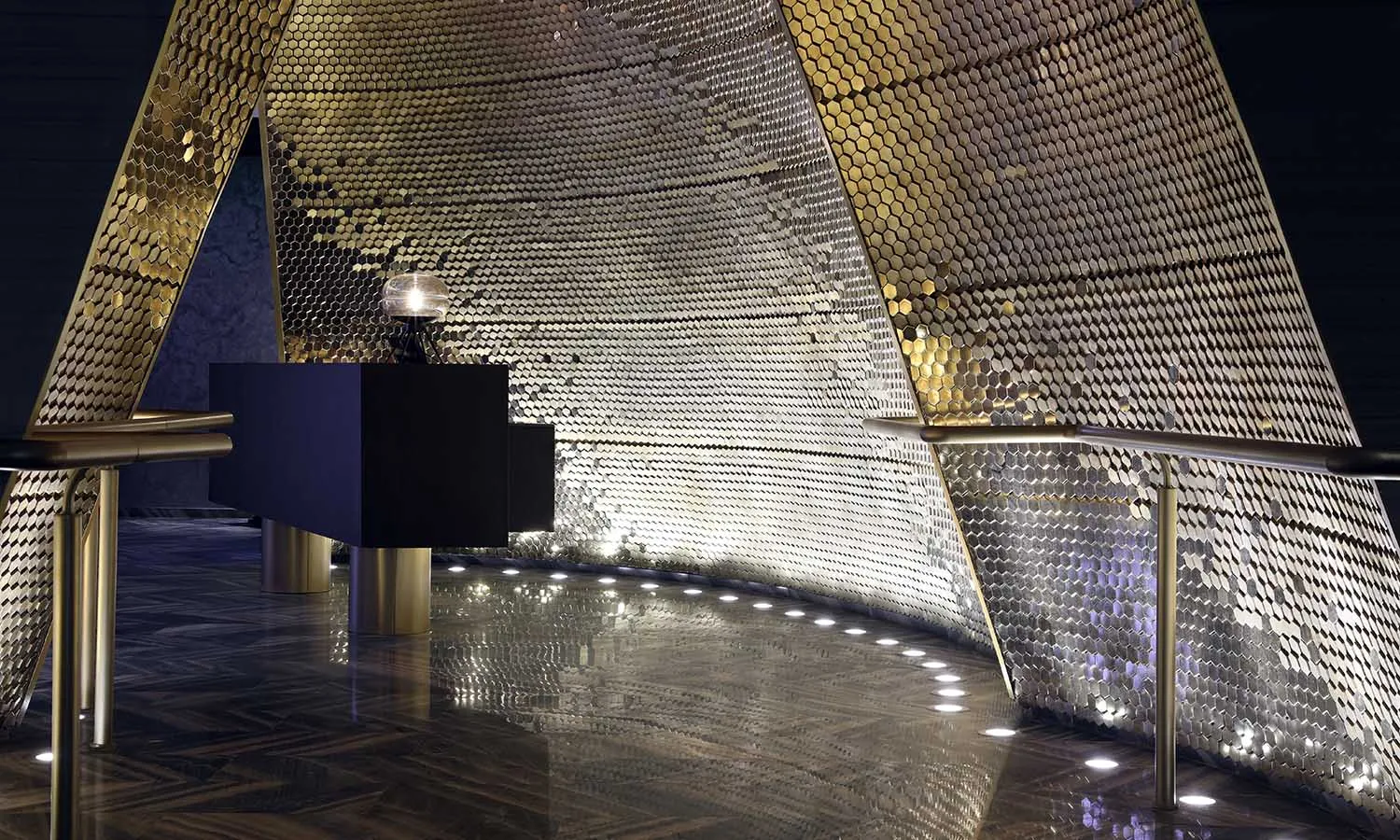 A modern lobby featuring a metallic hexagonal-patterned ceiling.