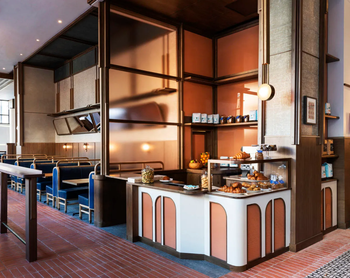 Modern restaurant cafe interior with seating, counter, and display case.