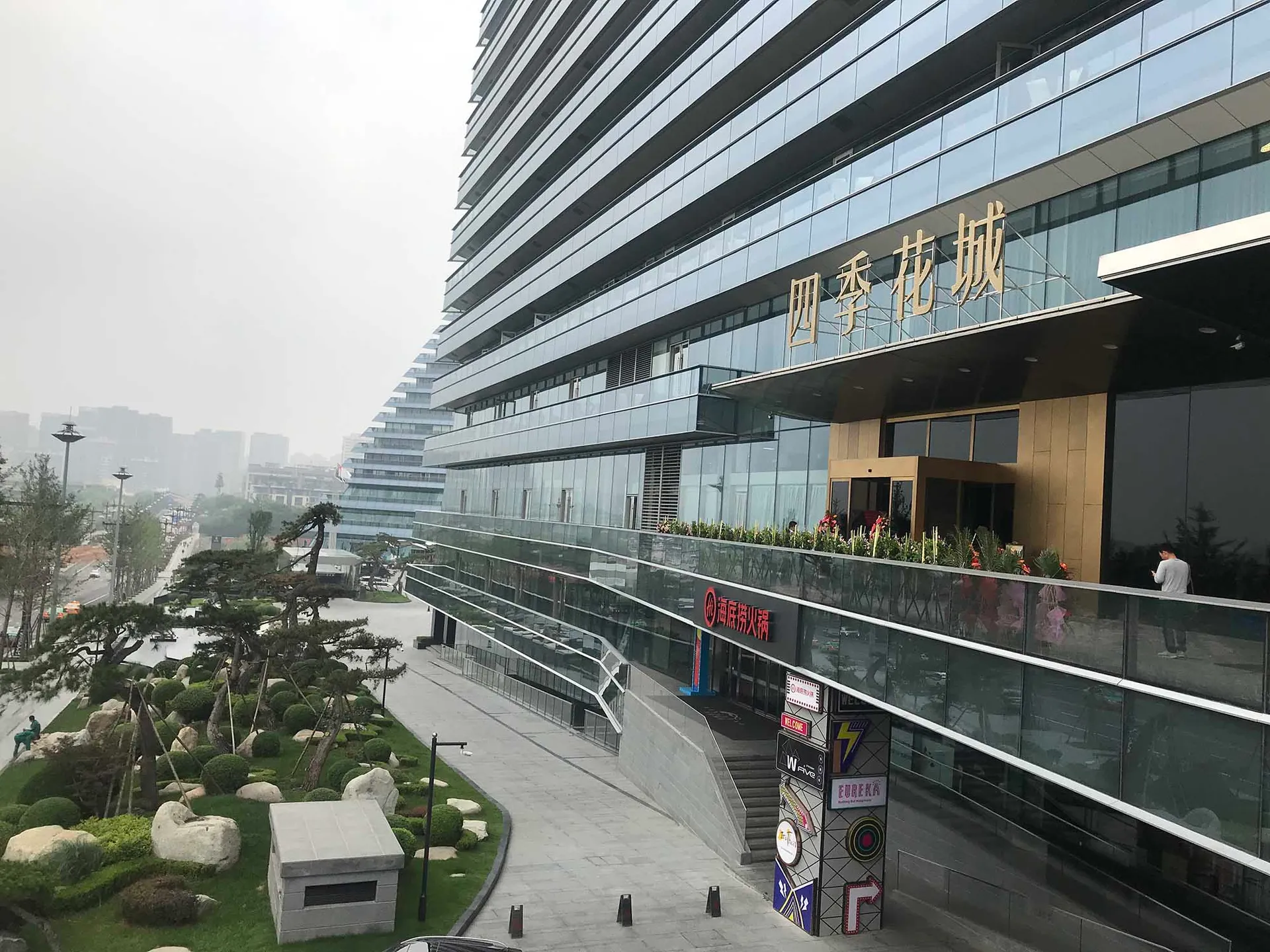 一座現代都市建築,擁有玻璃與混凝土外觀,搭配景觀步道。