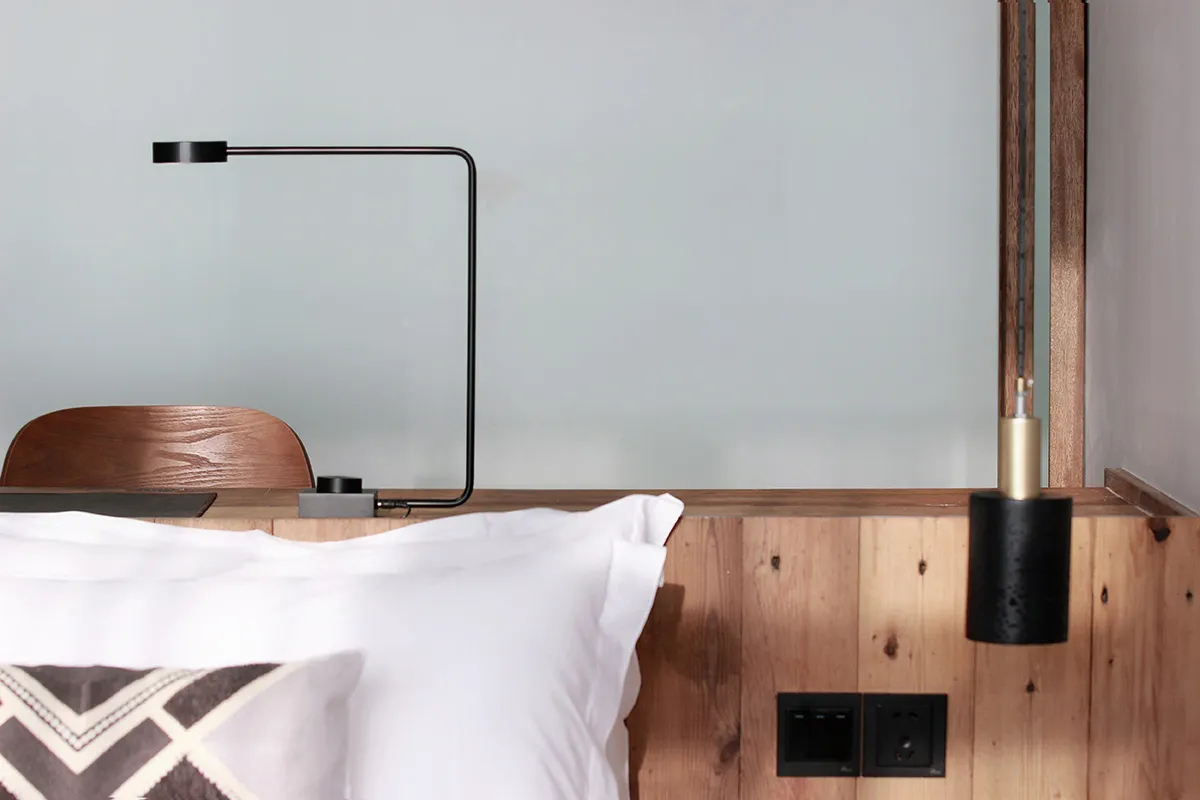 A minimalist bedroom featuring wooden walls and a white pillow.