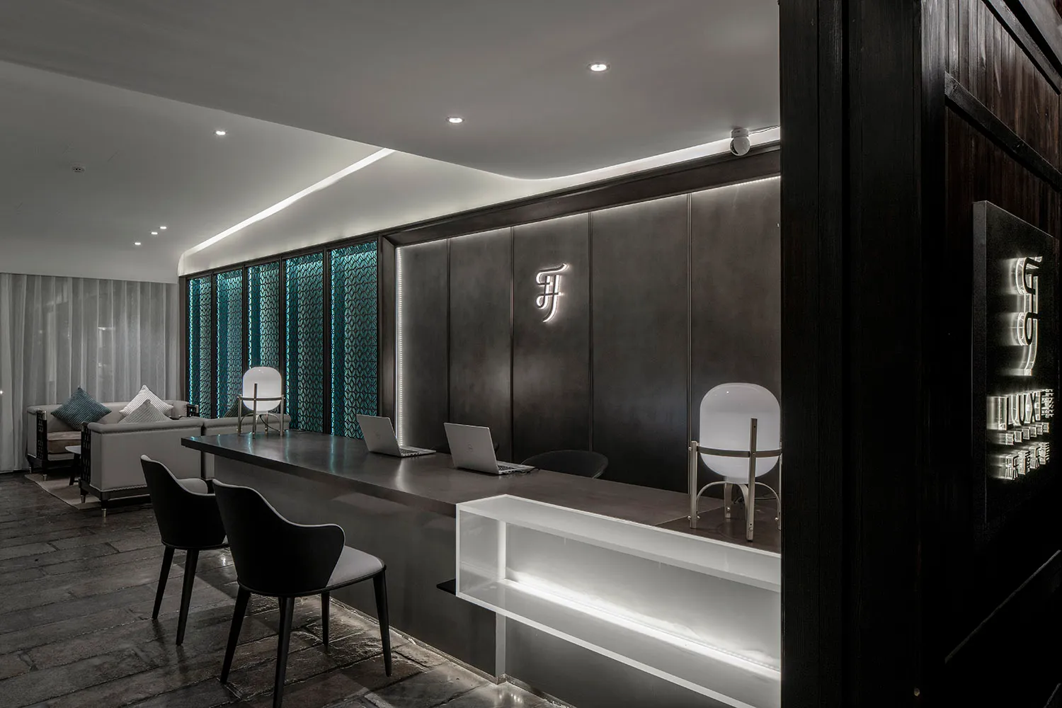 A modern lobby featuring a black metal counter and seating area with a branded logo on the wall.