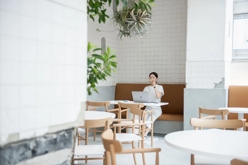 A minimalist cafe interior features clean lines, white walls, and a mix of materials, including wood and concrete.