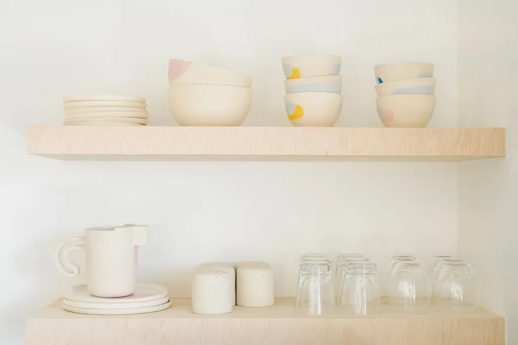 A minimalist kitchen featuring handcrafted ceramic dishes and utensils.
