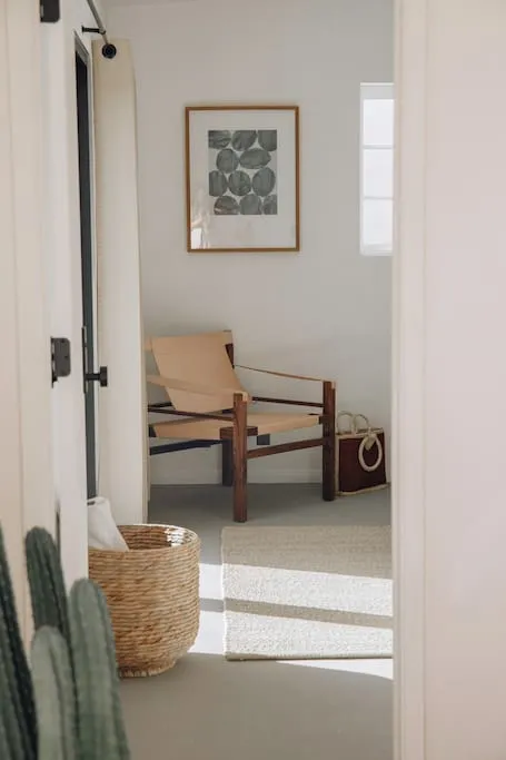 Minimalist living room with wooden furniture and a framed abstract artwork on the wall.