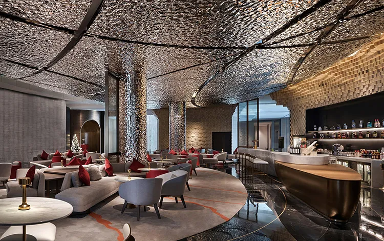 Modern lounge area with metallic textured ceiling, contemporary furniture, and a bar counter.