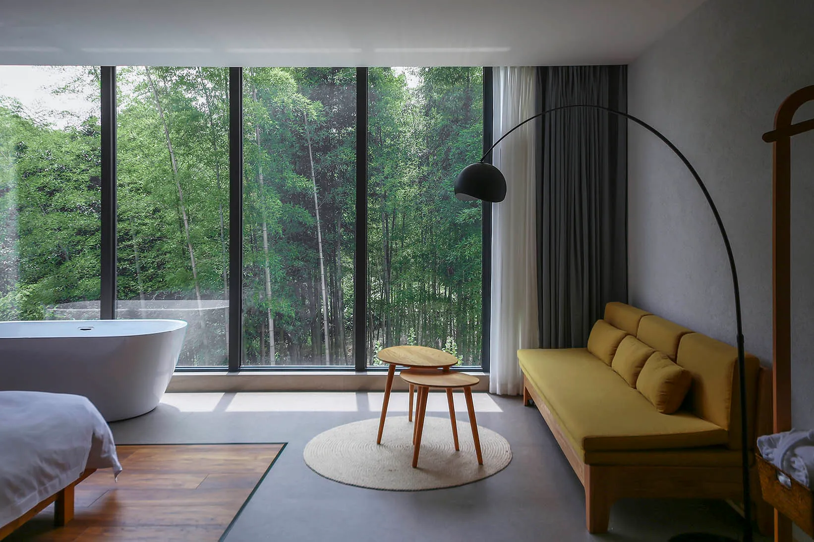Modern minimalist living room with concrete flooring, large windows, and a yellow sofa.