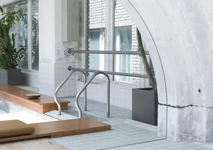 The image showcases a minimalist public space interior featuring concrete materials and industrial design elements.