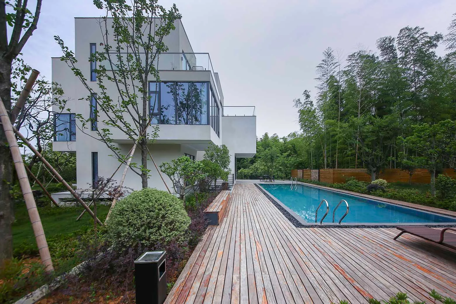 Modern white concrete house exterior with pool and deck.