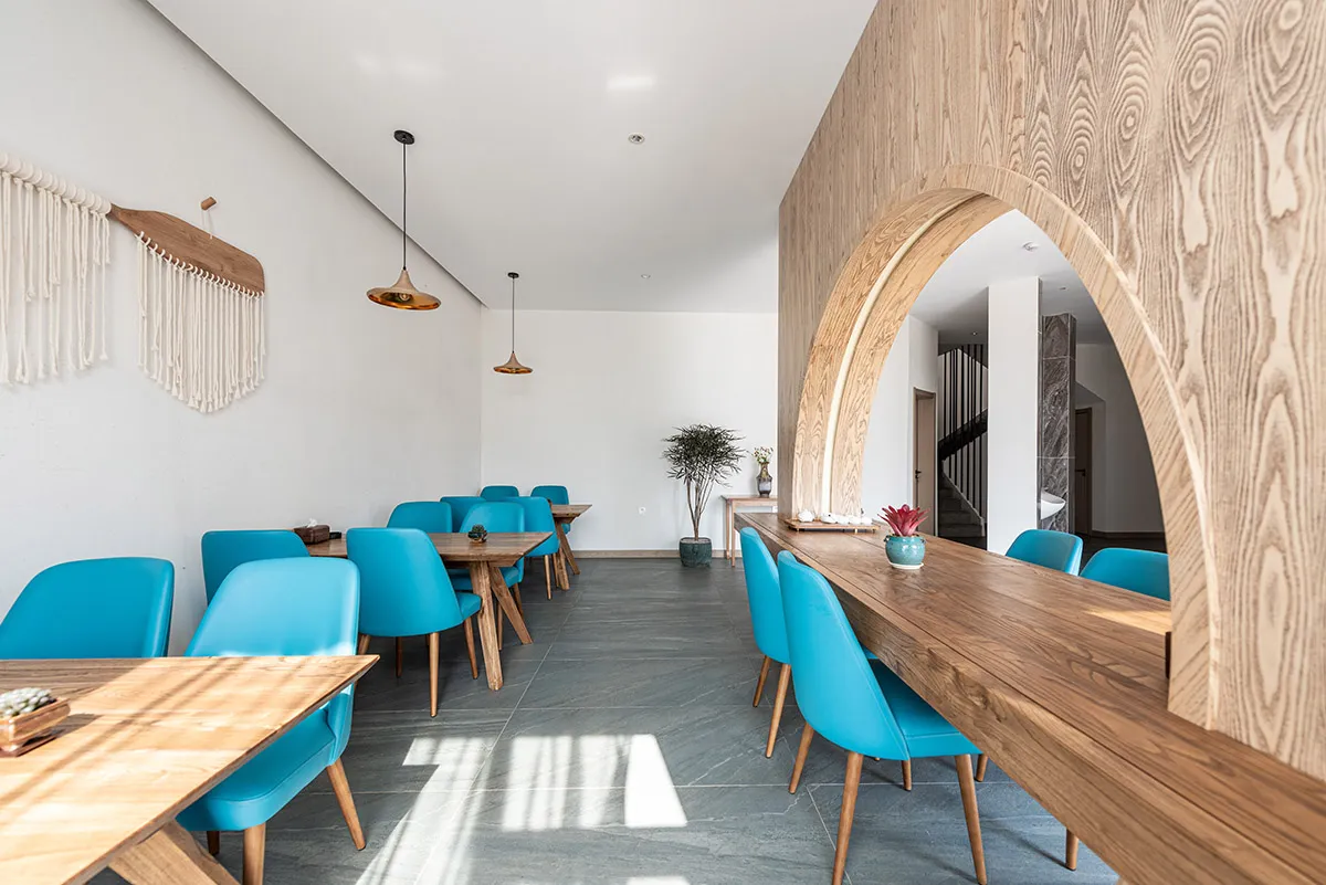 A cafe interior with wooden counters and blue plastic chairs.
