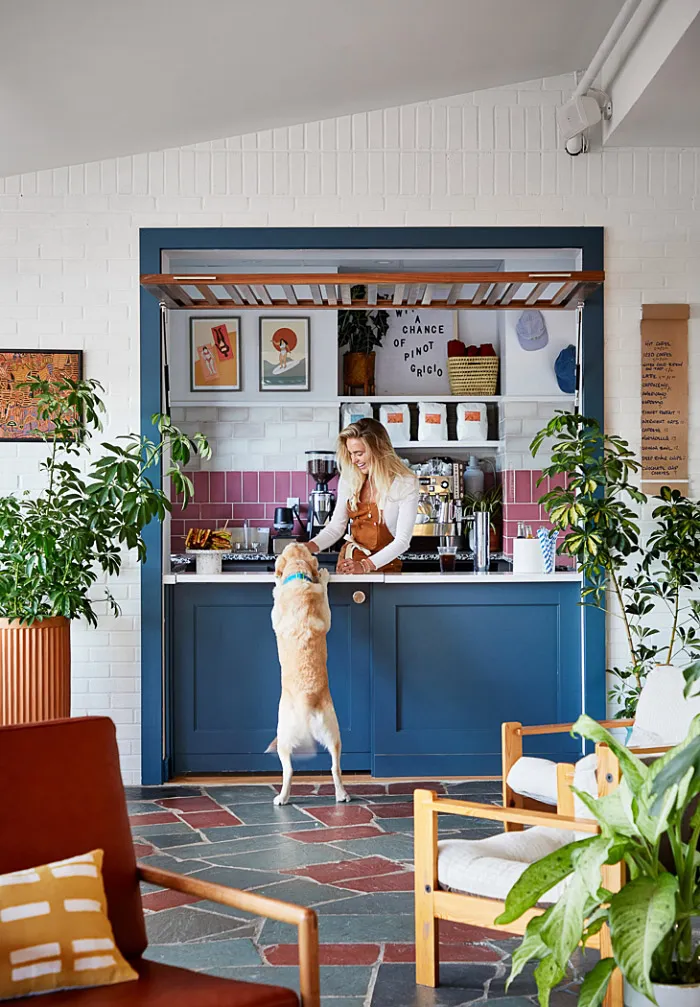 A modern home office featuring a tiled floor with a dog reaching for items on a countertop.