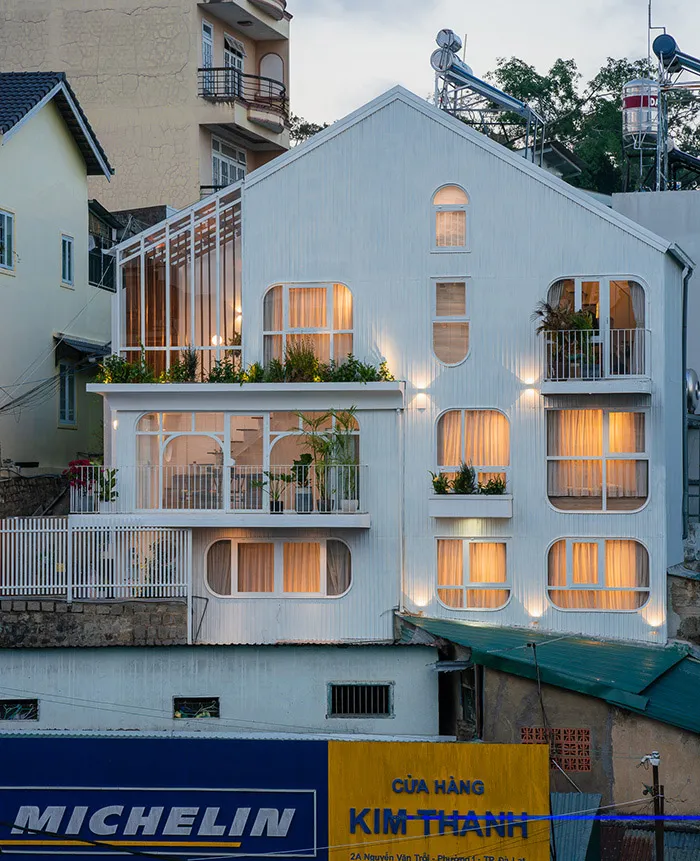 一棟白色嵌板建築,搭配大型窗戶與陽台。