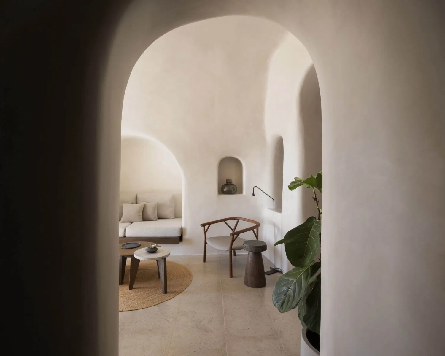 A minimalist living room with concrete walls, a circular coffee table, and a plant.