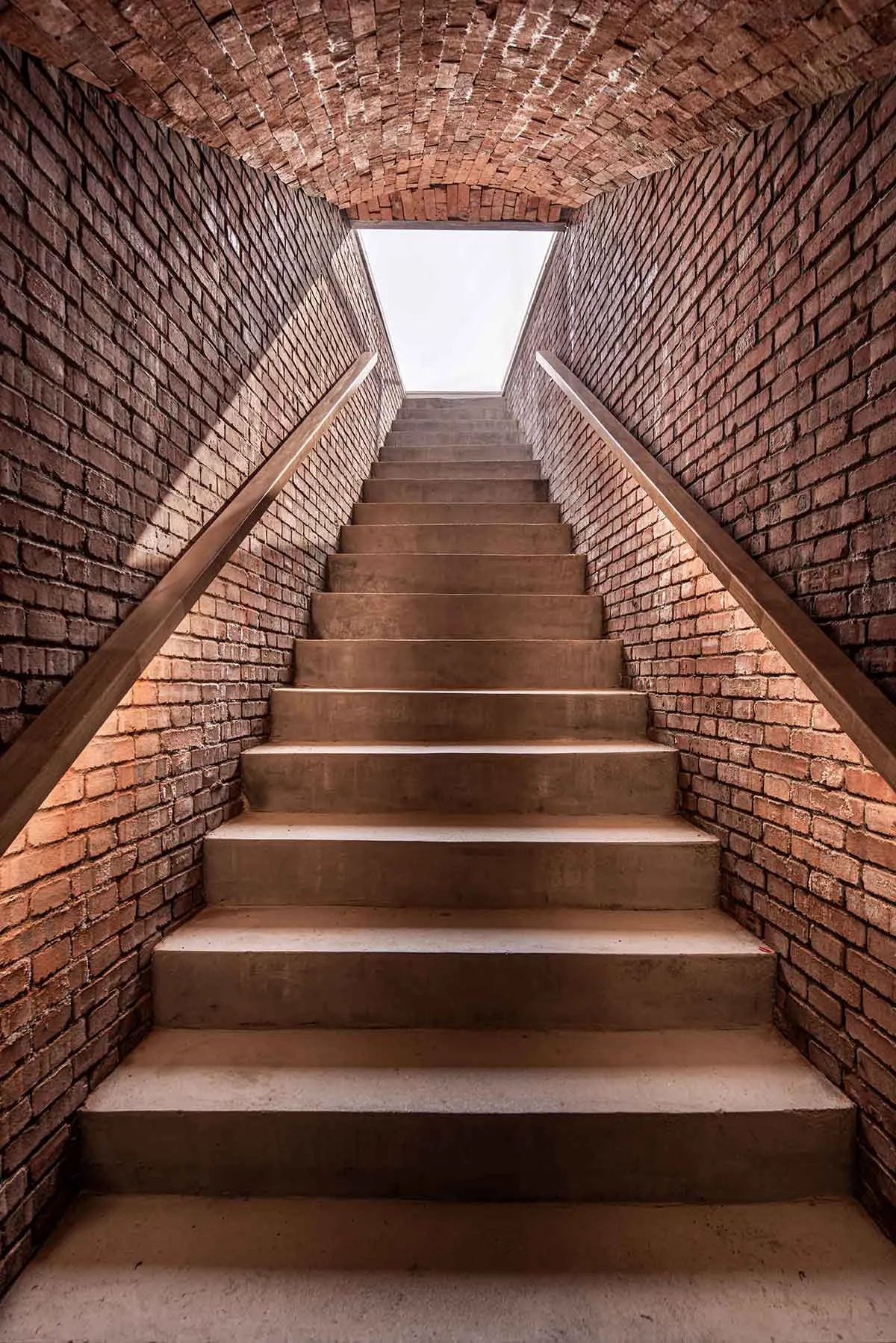 Indoor staircase with brick walls and a skylight at the top.