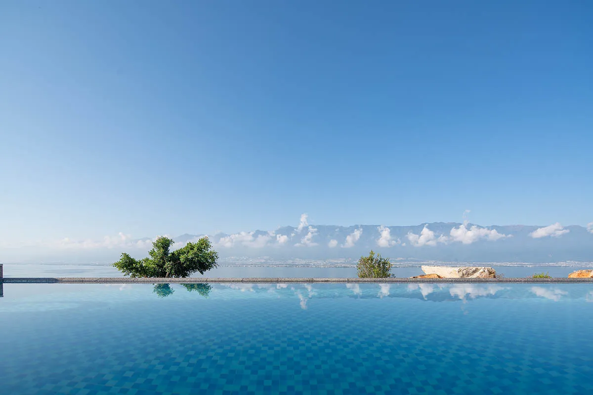 An infinity pool reflecting a blue sky with clouds.