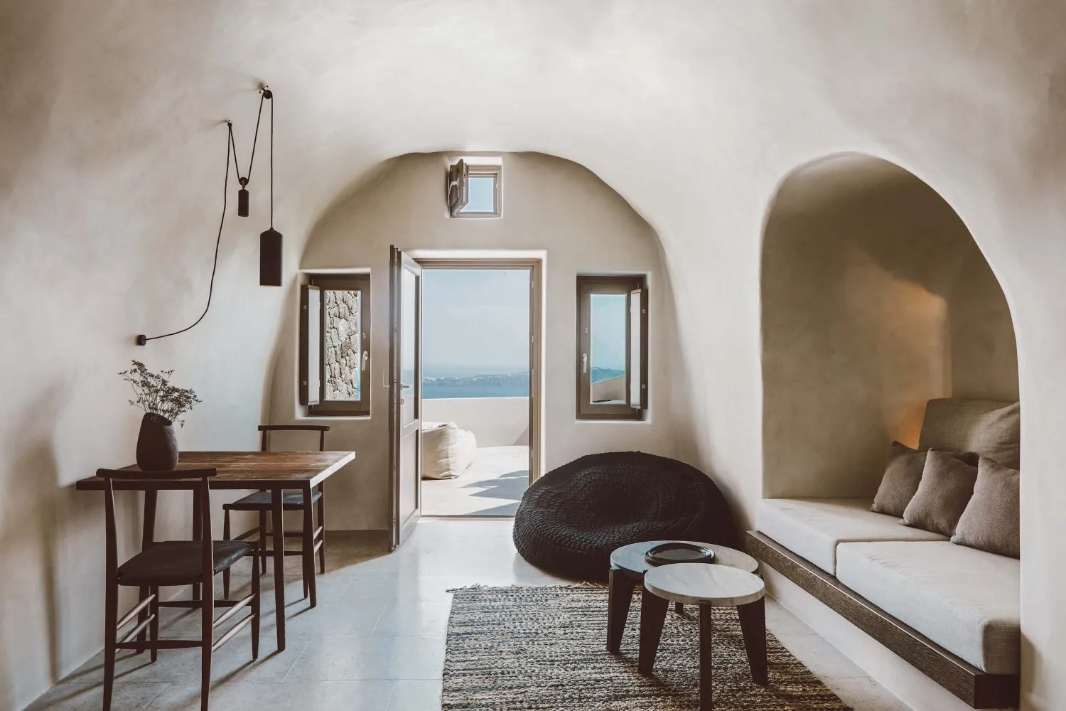 A minimalist living room featuring a concrete floor and white walls with an open view to the outdoors.