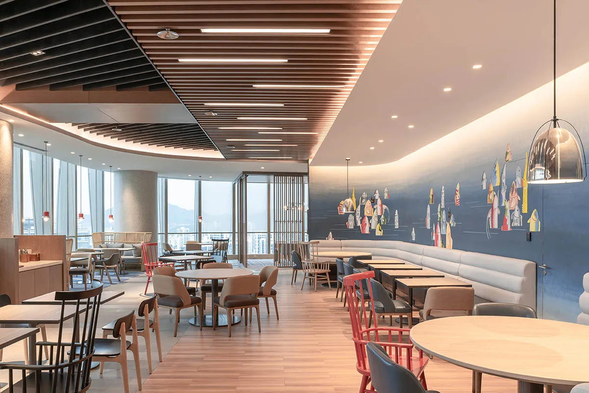 A modern cafe interior with wooden flooring, metallic pendant lights, and upholstered seating.