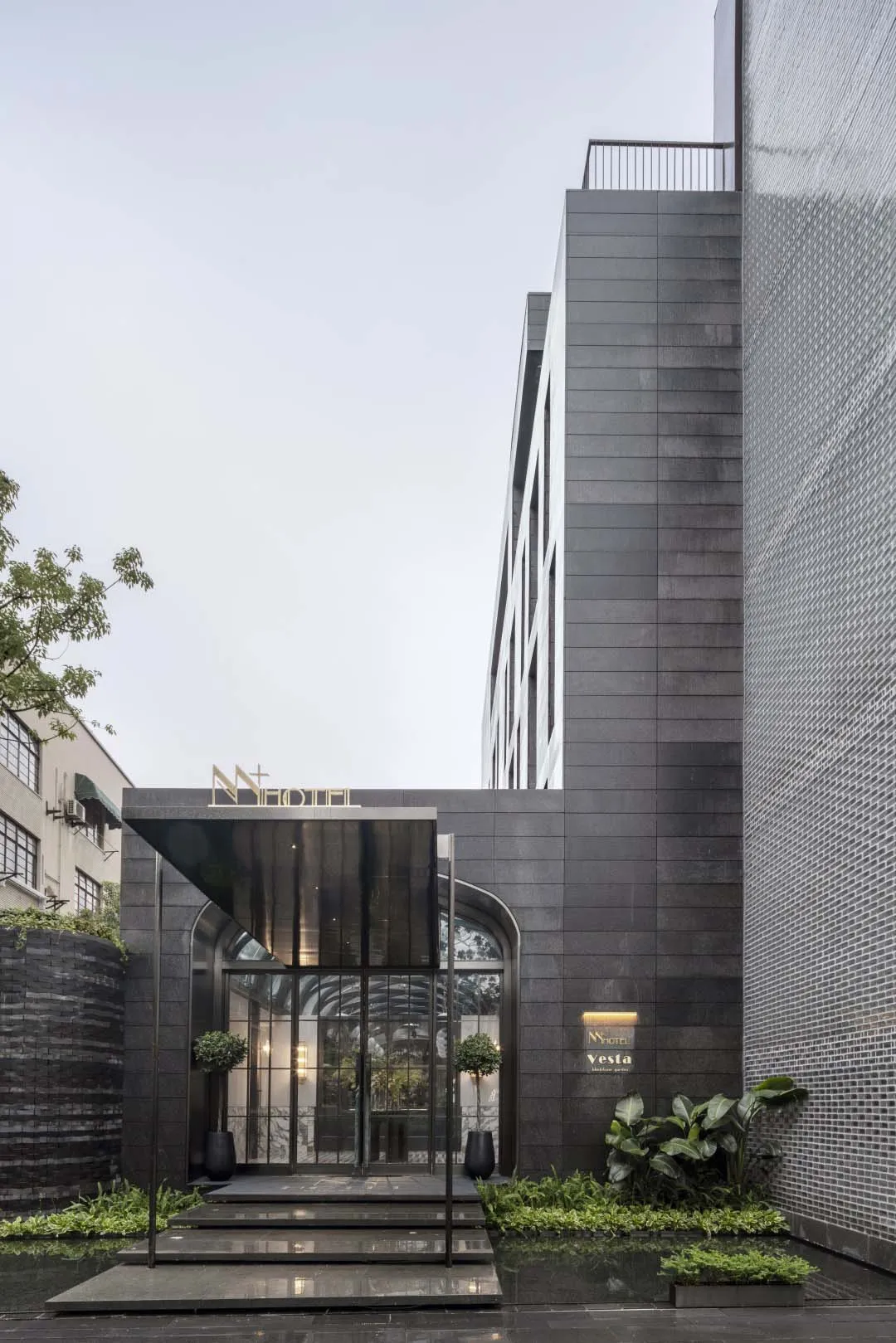 Modern hotel entrance featuring glass, metal, and stone materials