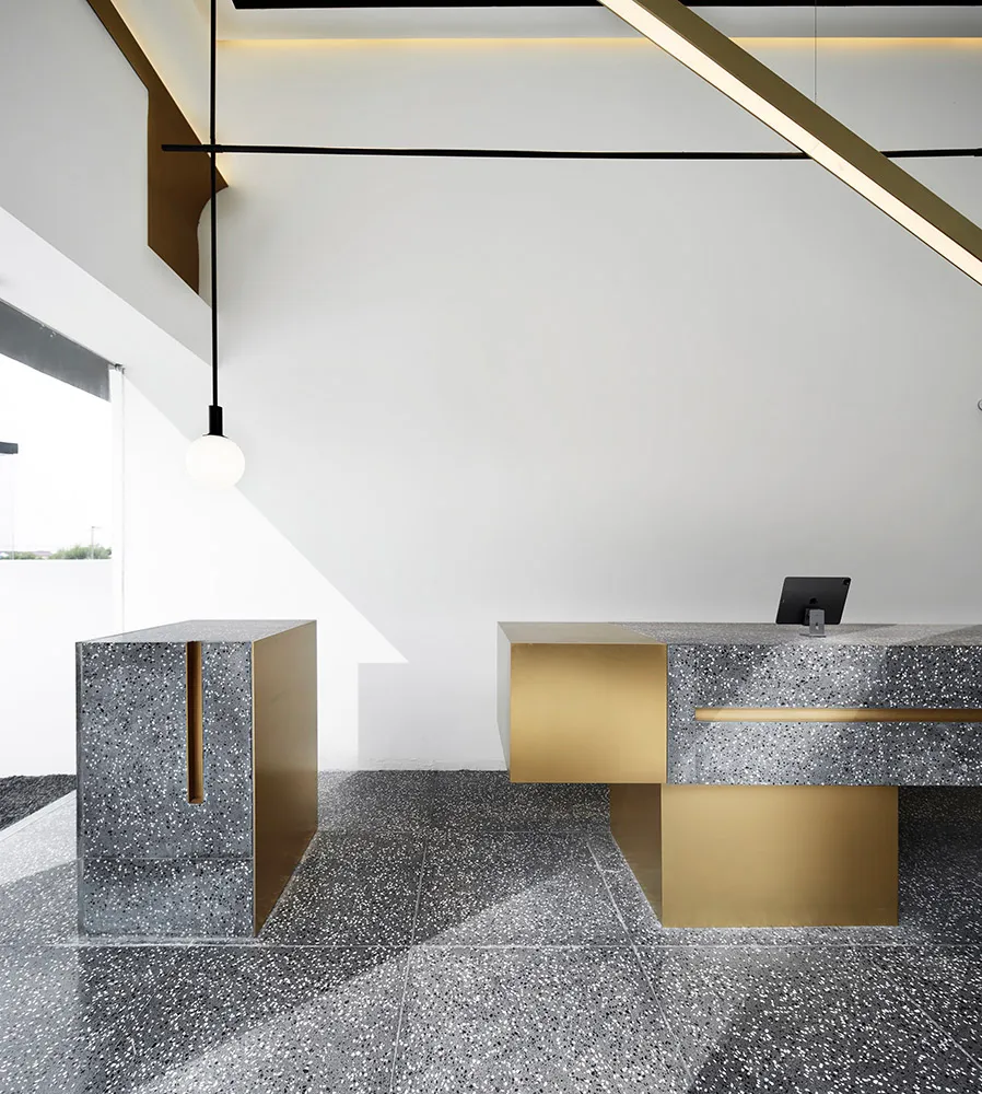 A modern industrial office front desk made of concrete and gold, featuring clean lines and minimalist design.