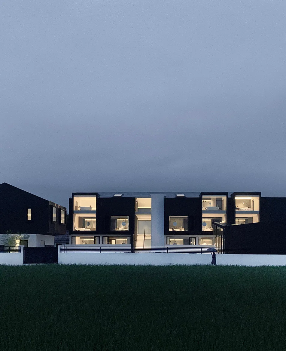 一座以混凝土與玻璃建造的現代住宅建築，擁有大面窗戶。