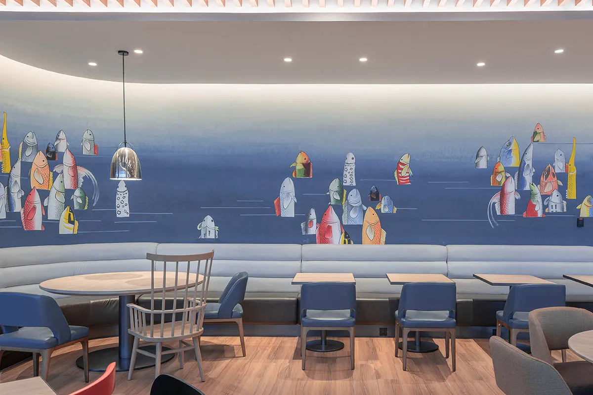 A modern restaurant interior featuring a colorful fish wall art mural.