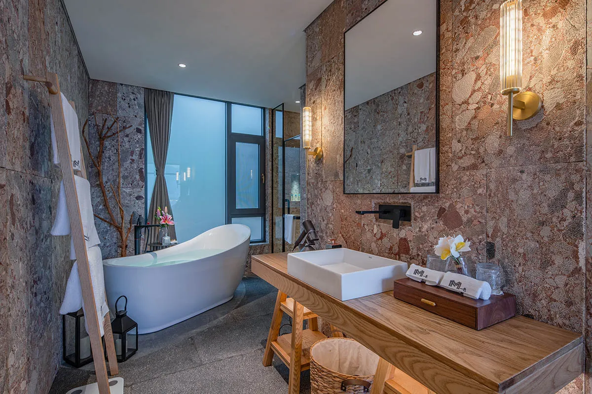 Modern bathroom with marble walls, freestanding tub, and wooden vanity.