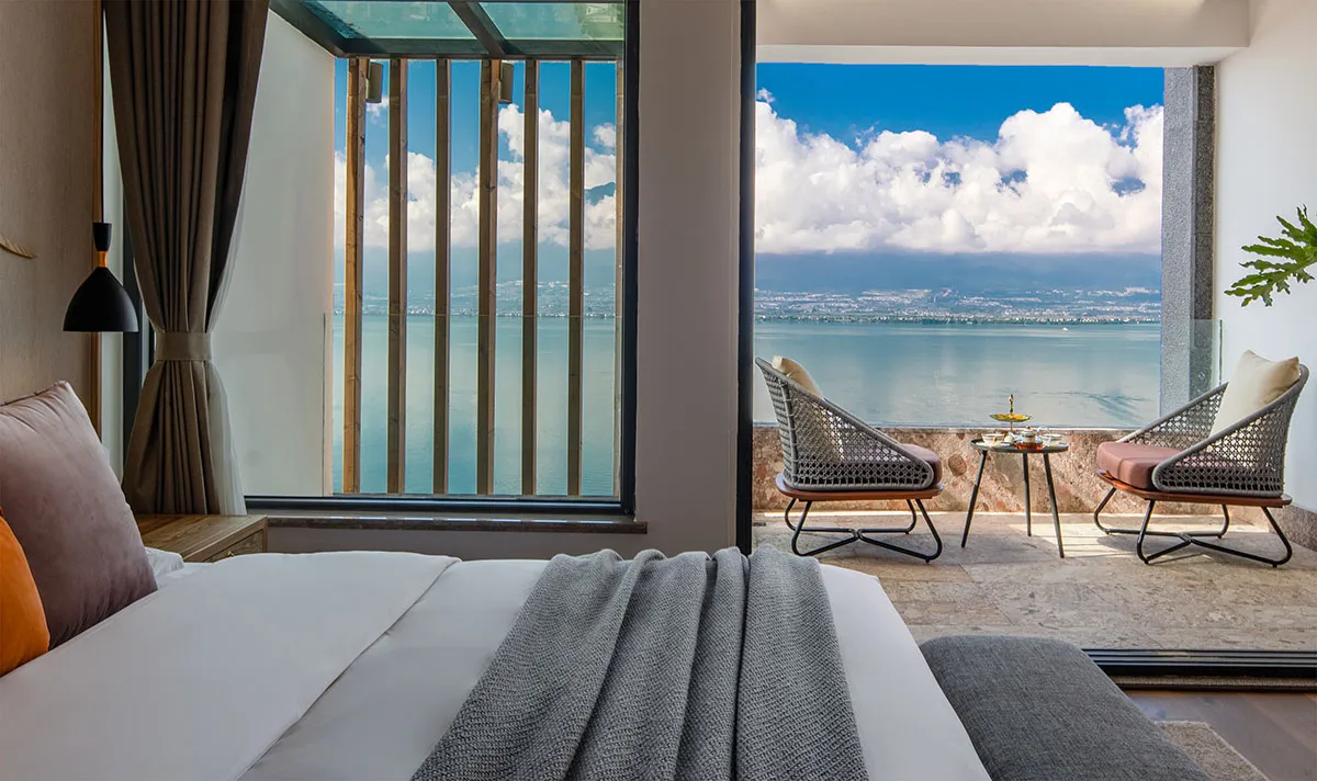 Modern bedroom with a seaview balcony, featuring minimalist furniture and a comfortable bed.