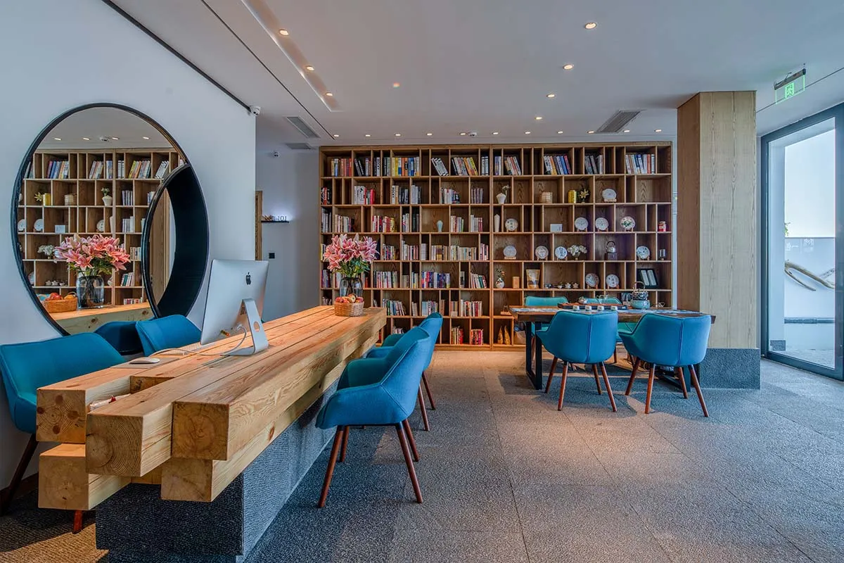 Modern commercial interior with industrial elements, including wooden furniture, floor-to-ceiling shelves, and large windows