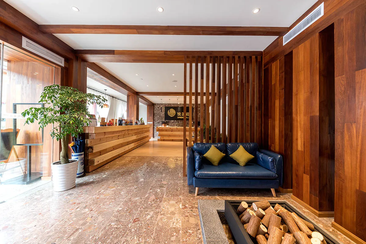 Modern lobby interior features a cozy seating area with a blue couch and wooden walls and floors.