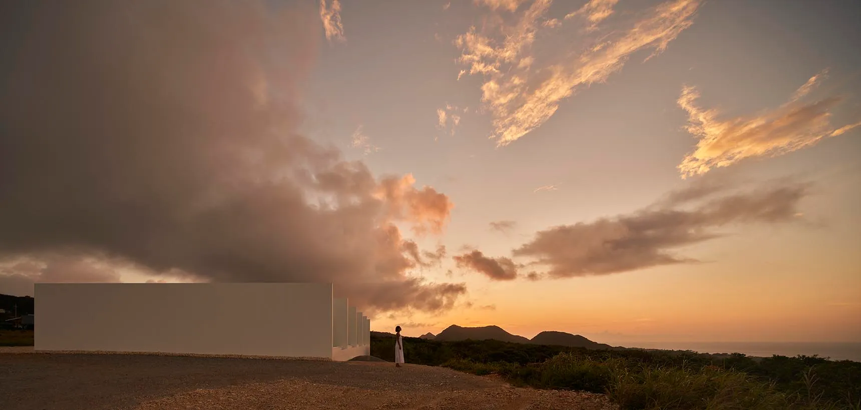 A serene outdoor scene with a cloudy sky and person standing near a building.