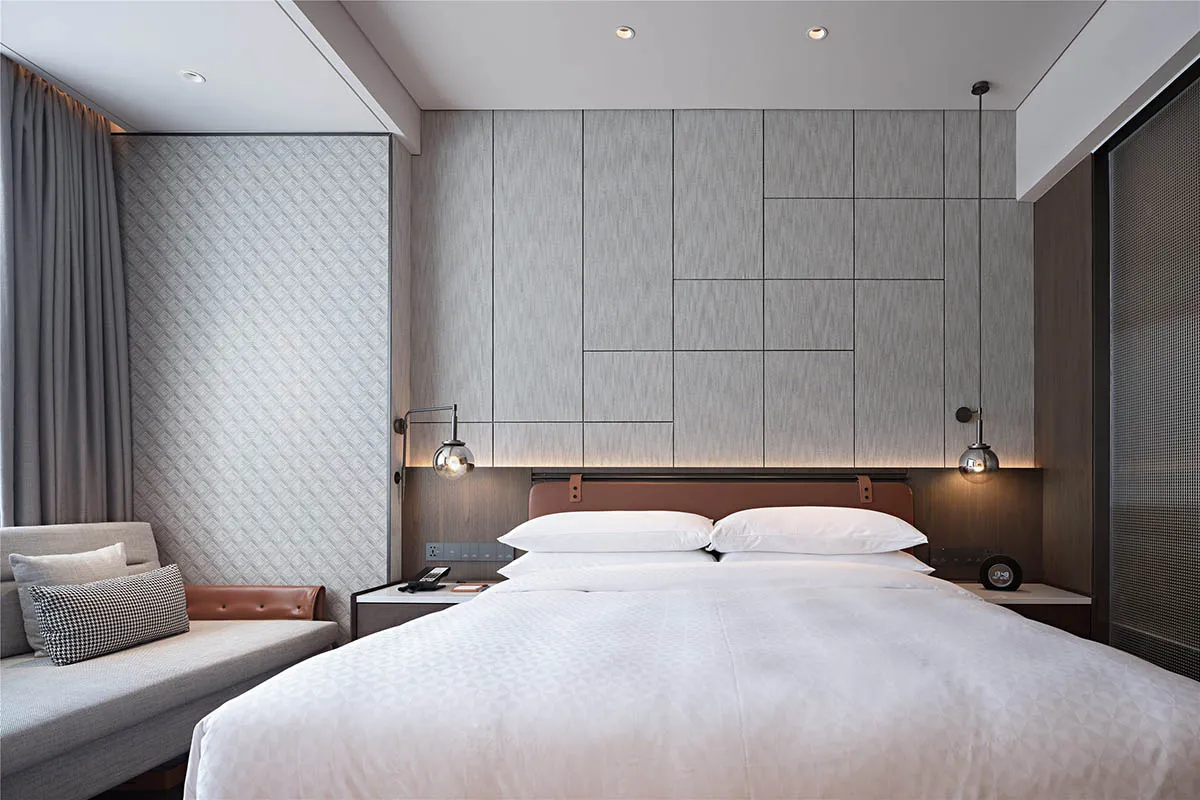 Modern minimalist bedroom featuring textured wall panels and a comfortable seating area.