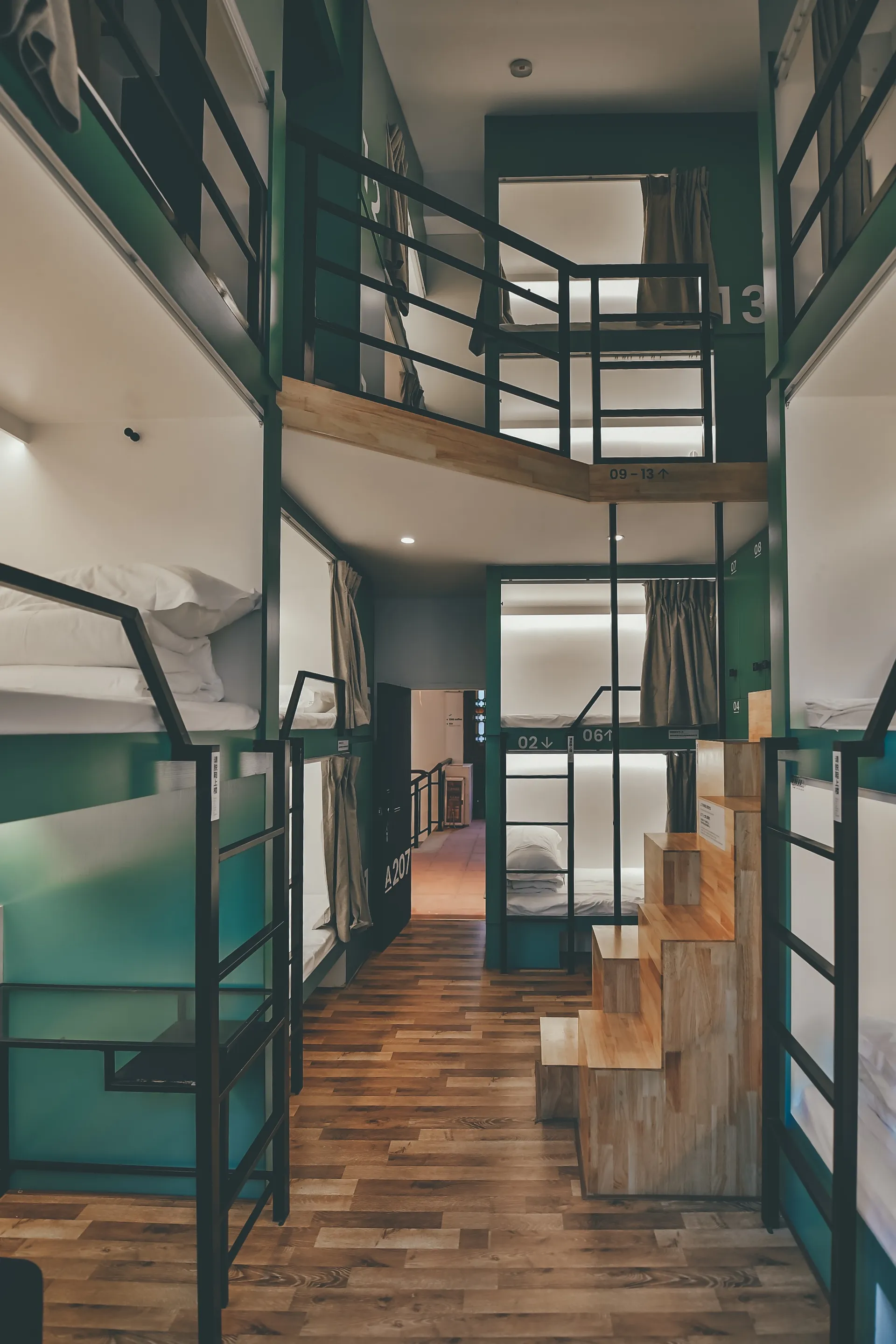 Industrial-style hostel room with steel and wooden furnishings and glass dividers.