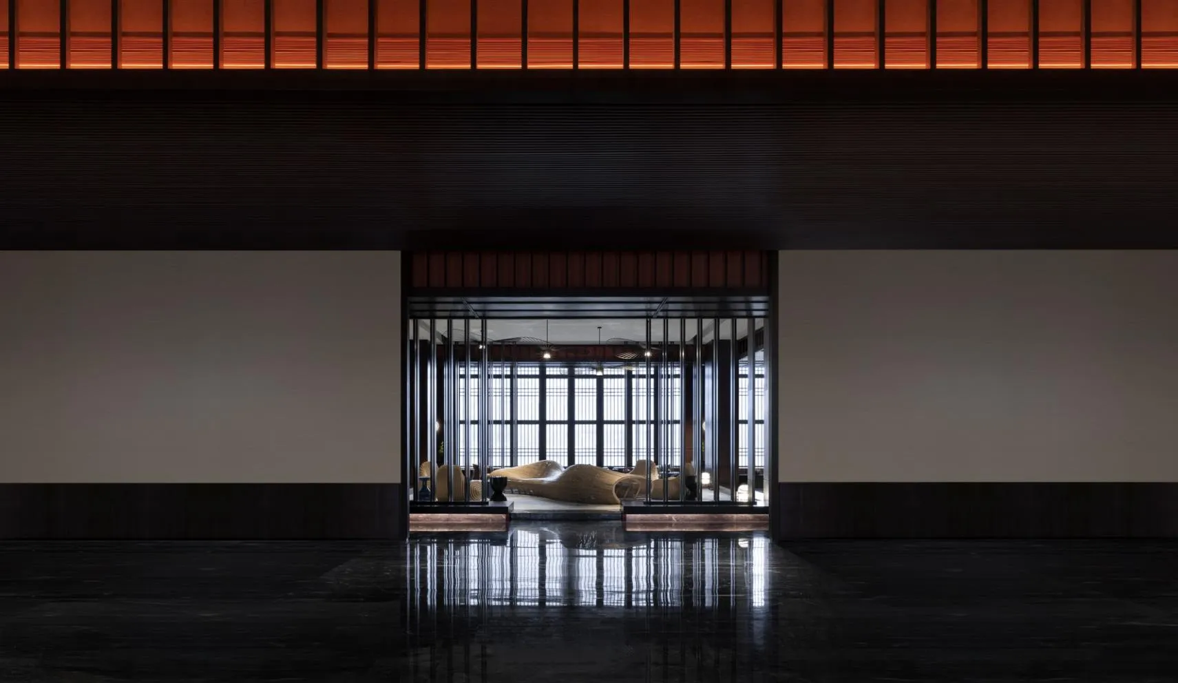 Interior view of a modern hotel lobby featuring wooden benches, glass walls, and metallic accents.