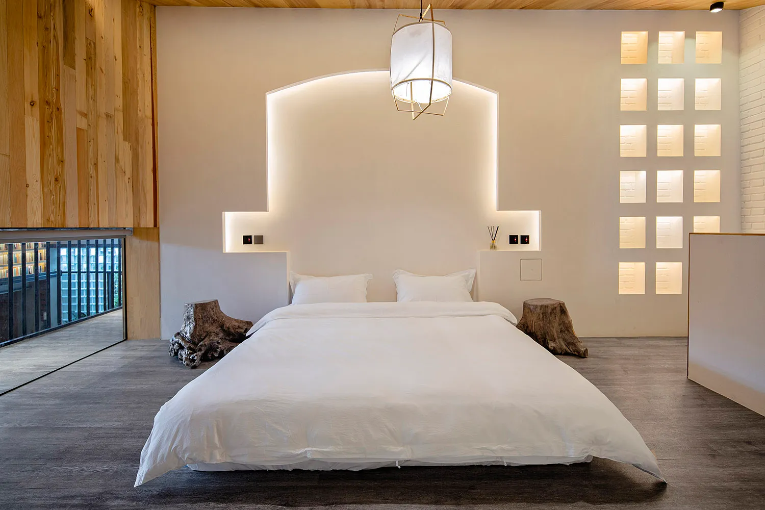 Clean, modern bedroom featuring concrete flooring, minimalist white decor, and a wooden headboard.