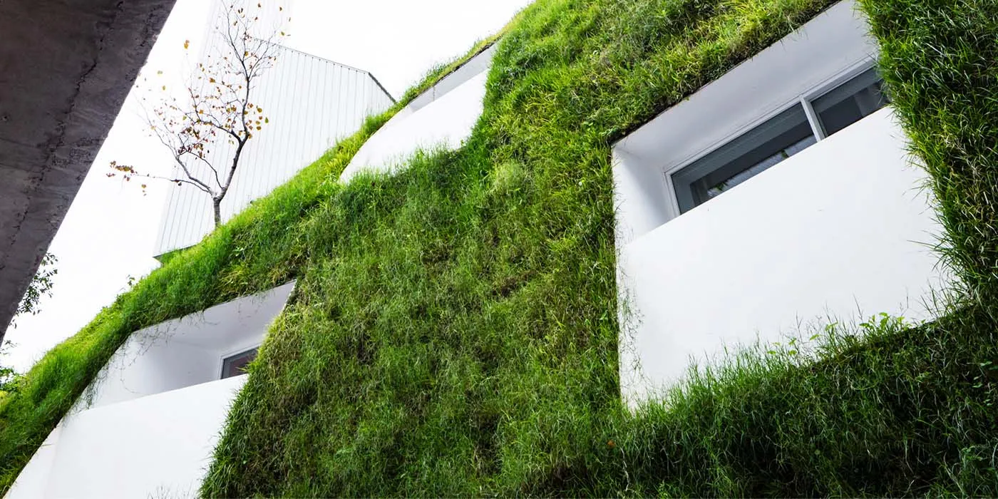 A modern building with green grass growing on the exterior.
