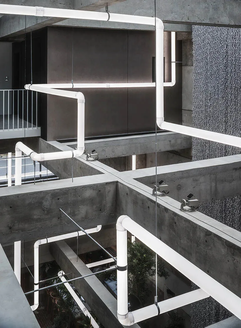 A modern industrial office space featuring exposed concrete pipes and minimalist design elements.