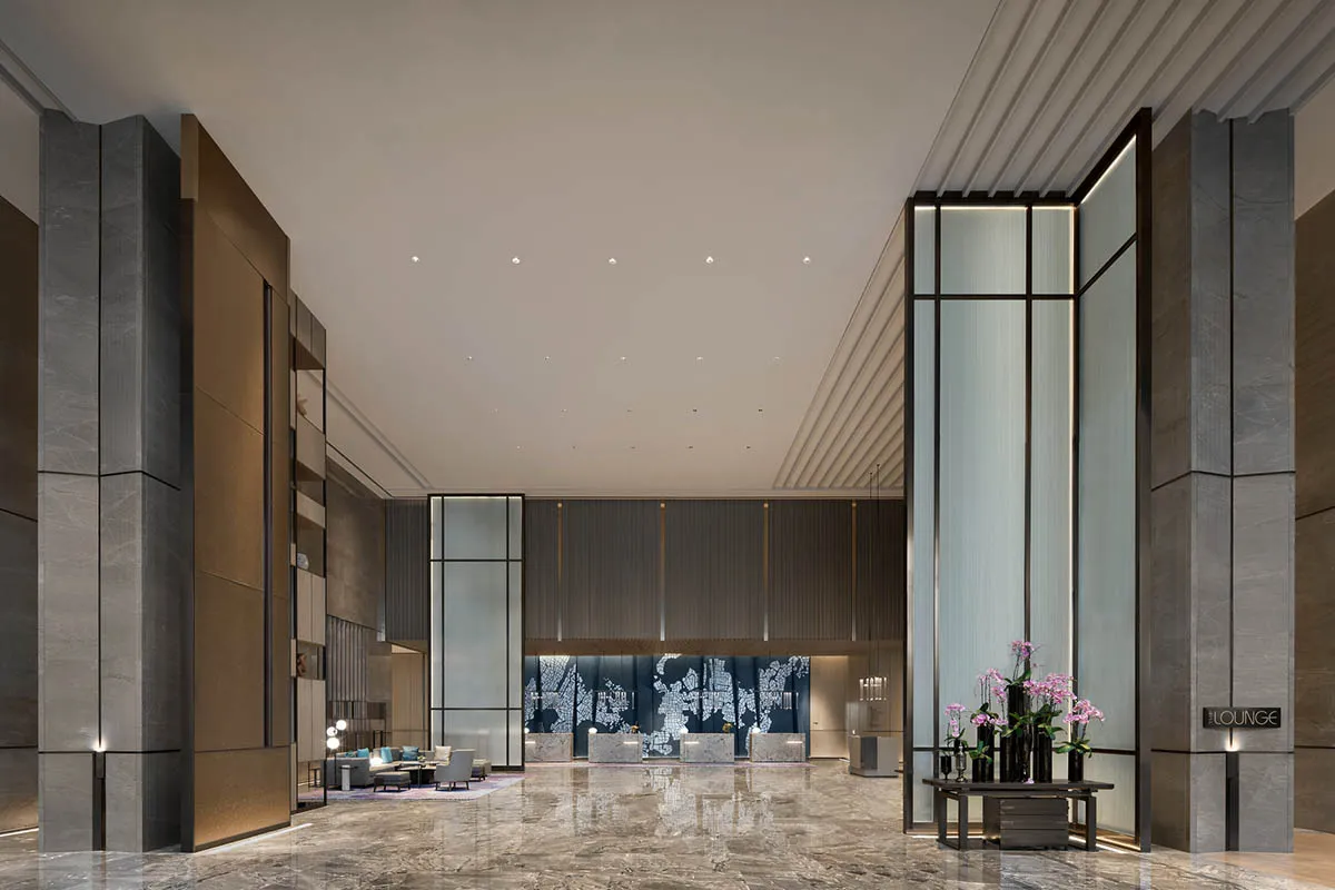 Modern hotel lobby featuring marble, glass, and metal materials and design.