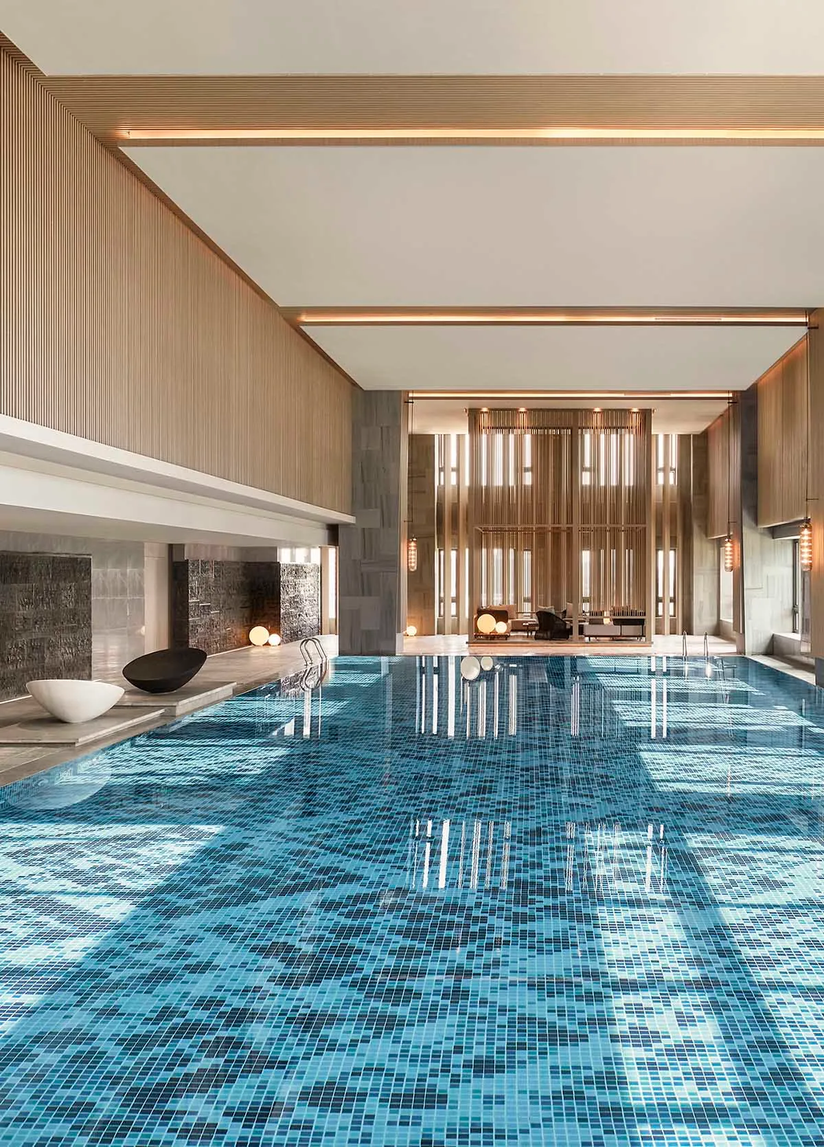 Modern indoor swimming pool with glass-tiled floor and wooden panelling