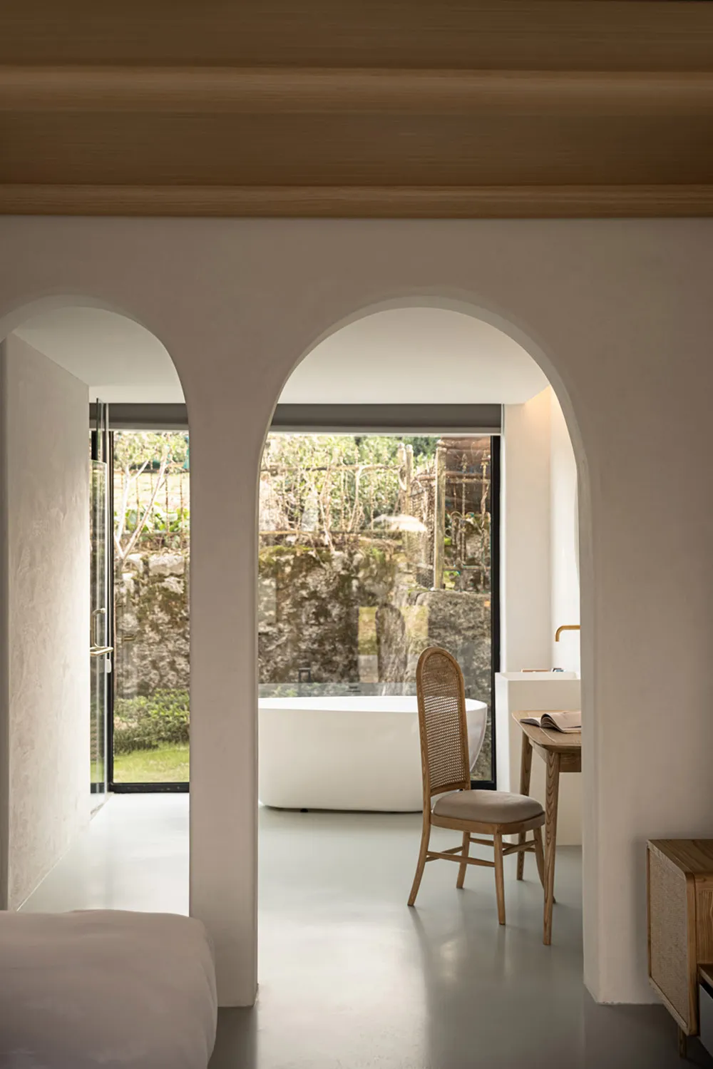 A minimalist bathroom with a white marble floor, walls, and bathtub.