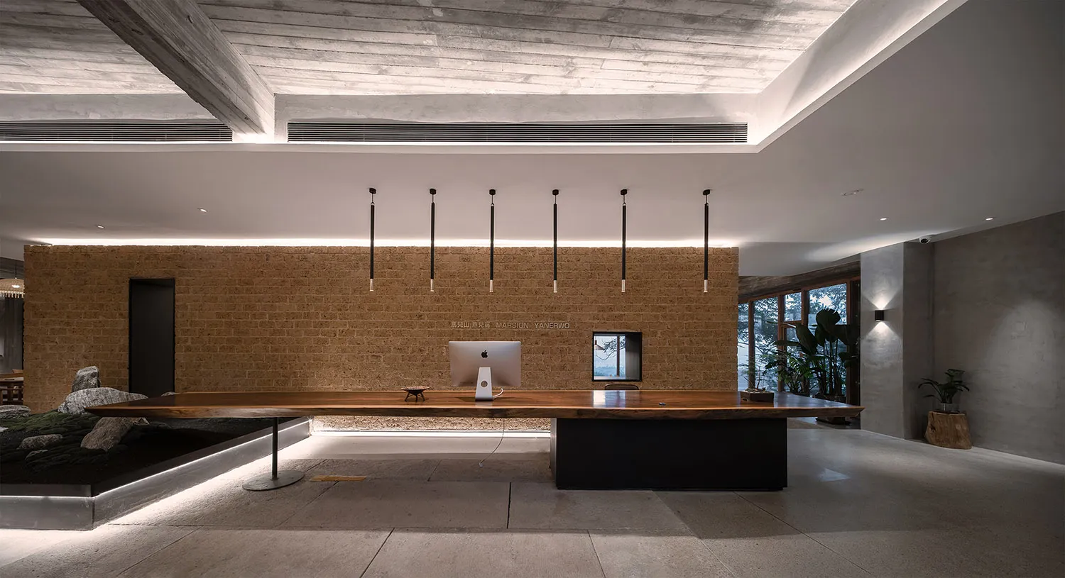 A minimalist office desk space with a wooden desk and hanging lights.