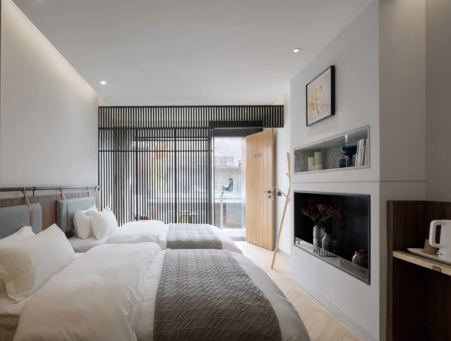 A modern minimalist hotel room with wooden furniture, metal accents, and glass doors.