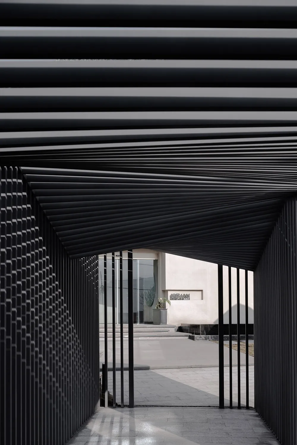 Modern, minimalist entrance featuring a metallic trellis and glass doors.