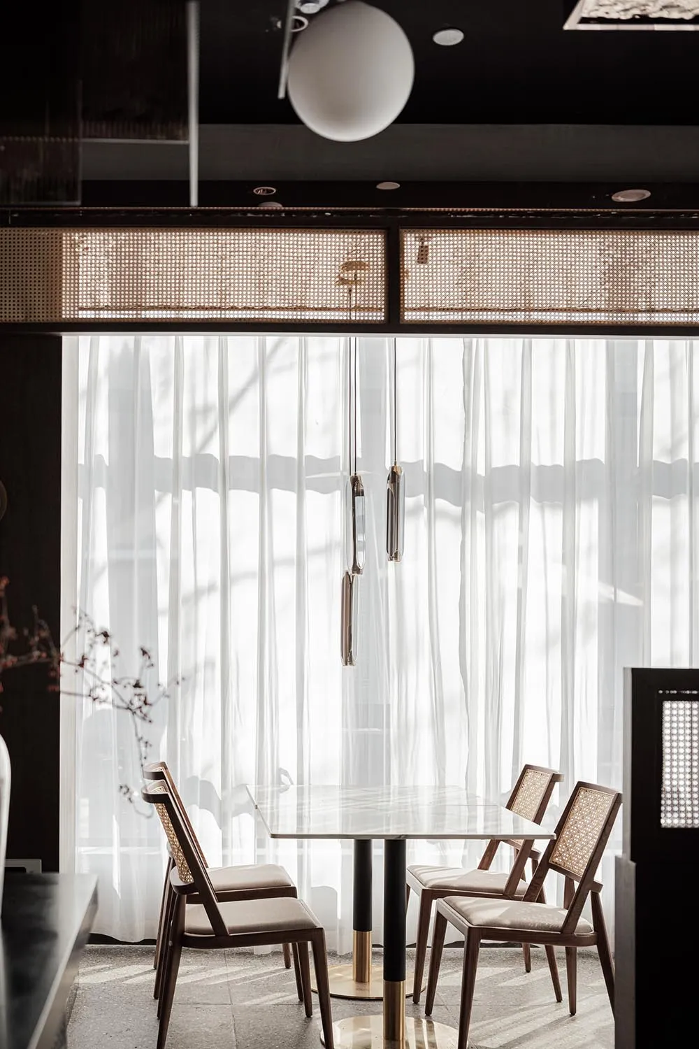 A minimalist interior space featuring glass, wood, and fabric elements.