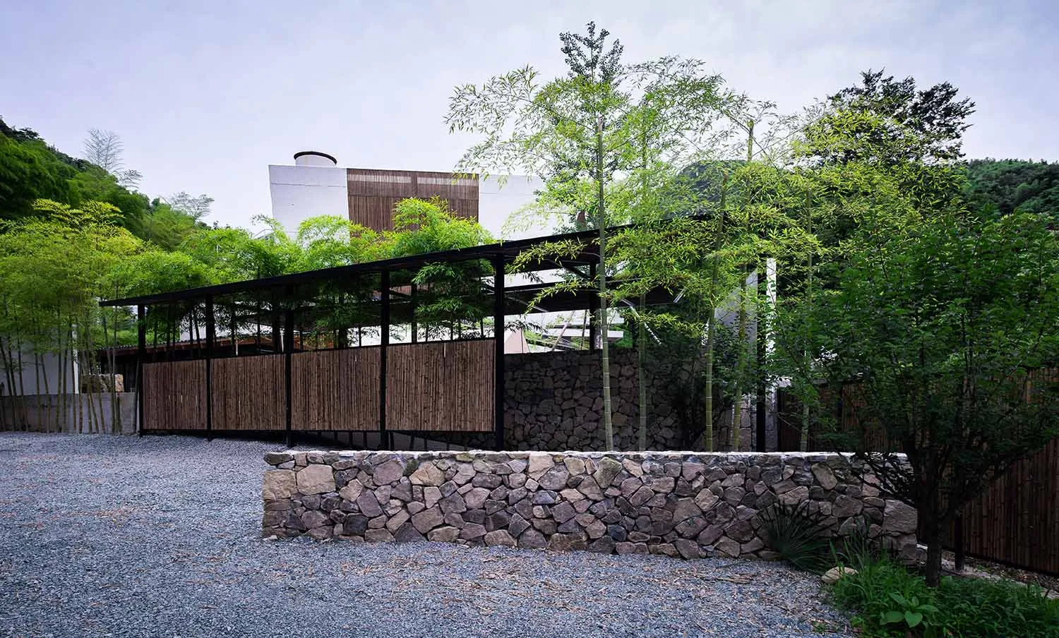 A modern landscape design featuring stone walls and a gravel path.