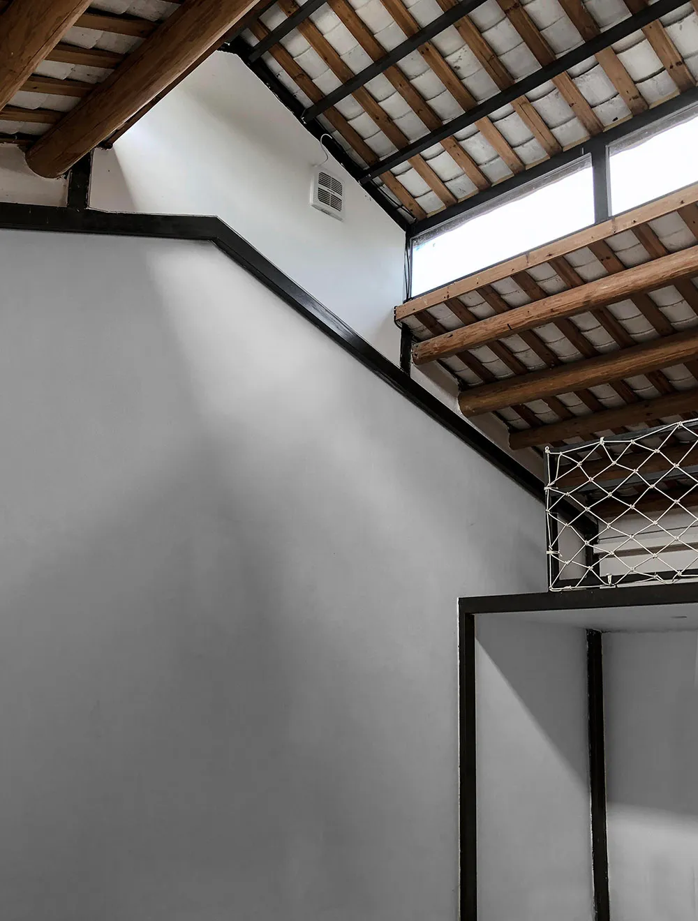 Modern minimalist staircase with wooden and concrete elements, featuring a skylight and light fixtures.